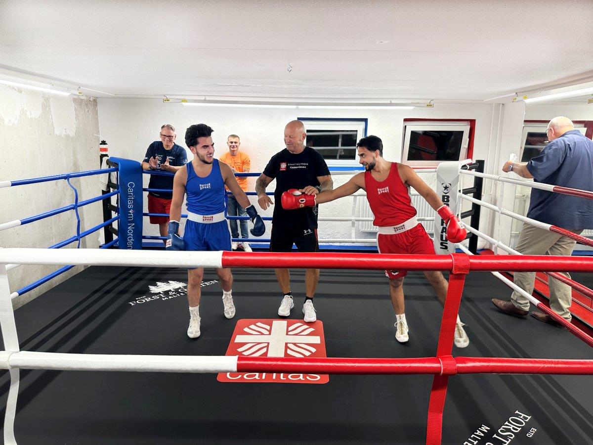 Zwei junge Männer mit ihrem Trainer im Boxring.