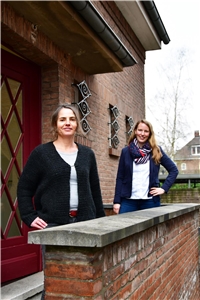 Das Foto zeigt zwei Frauen auf einer Treppe vor einem Gebäude.