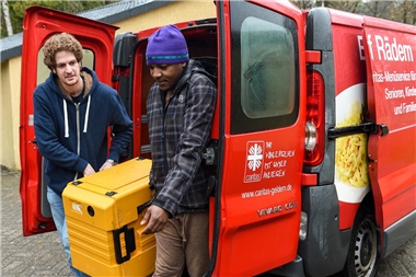 Zwei Männer laden Kiste aus Lieferwagen
