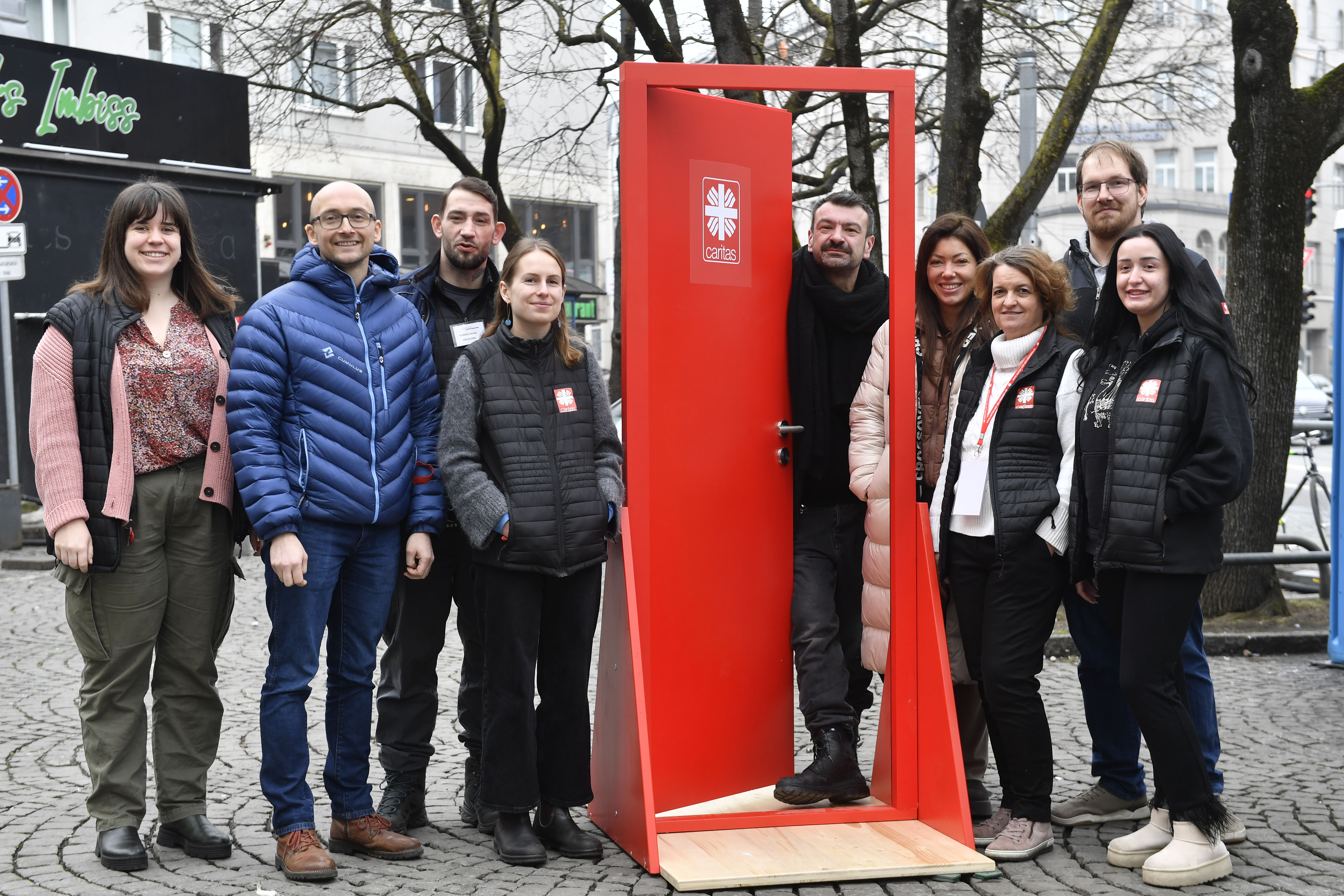 Die Teilnehmer*innen des Sozialspaziergang stehen neben der roten Tür.
