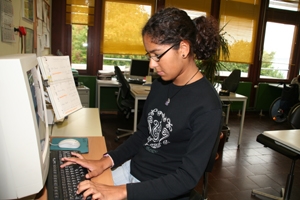 Es ist eine Werkstattmitarbeiterin an einem Computer zu sehen. Sie trägt einen schwarzen Pullover.