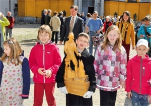 Kinder der Schule für alle tragen die Holzfigur des heiligen Florian von der Stiftskirche zur St. Florian-Stiftung.