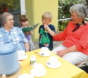 Kinder der Kita unterhalten die Senioren während an der Kaffeetafel
