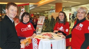 Caritas-Mitarbeiterinnen in ihren roten T-Shirts an ihrem Stand im Gespräch mit Michael Kretschmer.