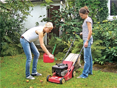 Zwei junge Frauen mit Rasenmäher bei der Gartenarbeit