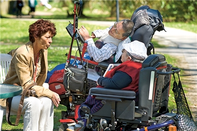 Frau im Gespräch mit zwei behinderten Rollstuhlfahrern des Wohnheims