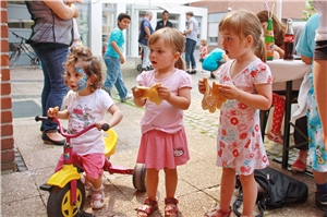 Auf dem Foto stehen drei rosa gekleidete Kleinkinder