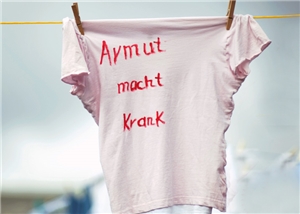 Shirt Armut macht krank (quer) T-Shirt mit der Aufschrift 'Armut macht krank' an der Wäscheleine