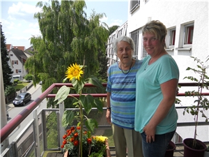 Eine Bewohnerin und eine Mitarbeiterin freuen sich über die selbstgezogene Sonnenblume