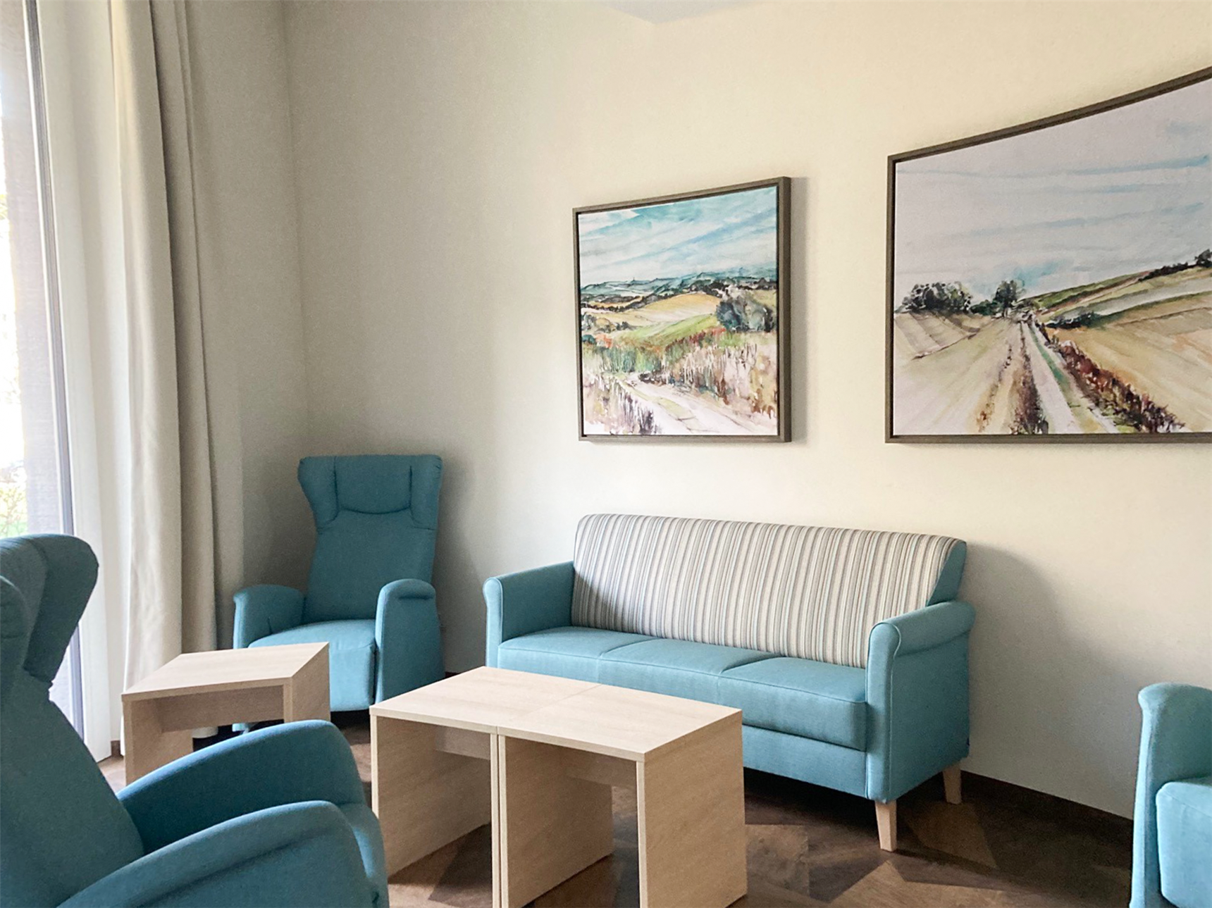 Raumausschnitt mit blauen Sofa und Sesseln und hölzeren Tischen