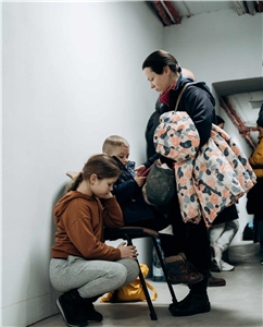 Eine Frau steht im Luftschutzkeller, zwei Kinder sitzen vor ihr. 
