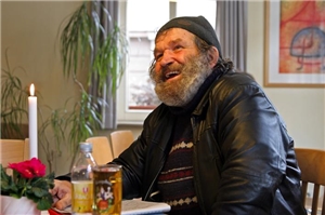 Stifterprojekte Menschen ohne Wohnung Lachender Mann am Tisch in der Olgastraße 46
