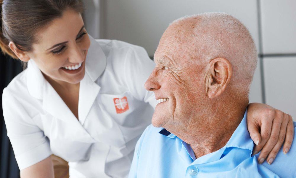Pflegekraft steht hinter Senior
