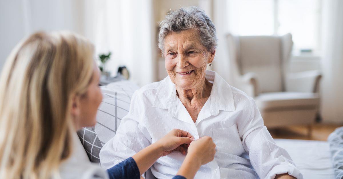 Pflegehilfskraft unterst�tzt Seniorin beim Ankleiden