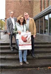 Organisatorin Ruth Tempelaars (Caritas), der musikalische Leiter Johannes Esser und Caritas-Vorstandssprecher Dirk Hucko (li.) präsentieren vor der Marienkirche das Konzertplakat. Organisatorin Ruth Tempelaars (Caritas), der musikalische Leiter Johannes Esser und Caritas-Vorstandssprecher Dirk Hucko (li.) präsentieren vor der Marienkirche das Konzertplakat.