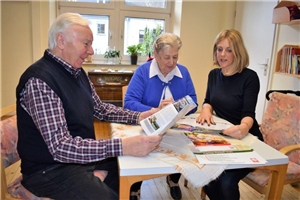 Frau zeigt einem älternen Ehepaar den Katalog