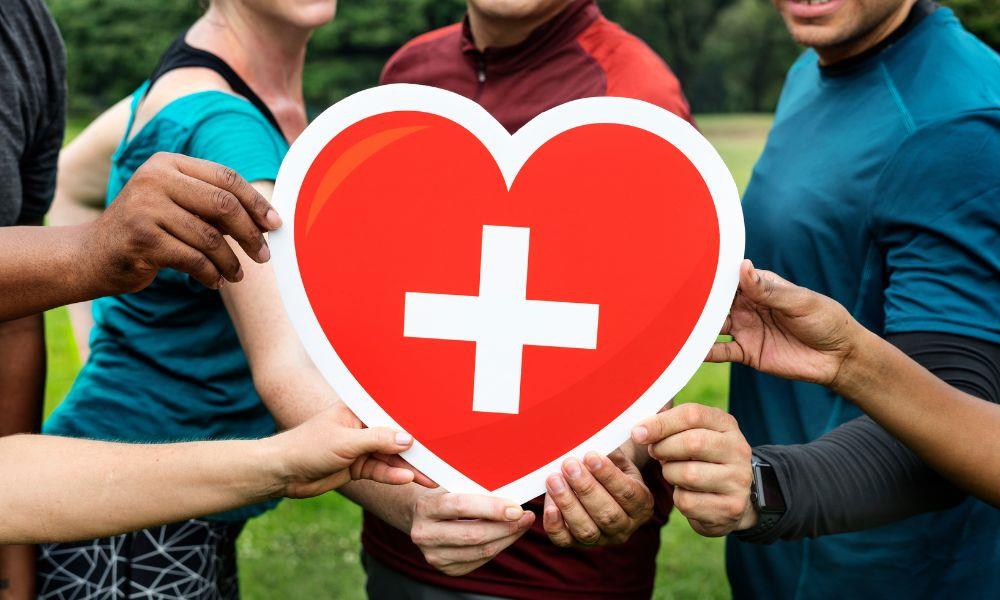 Diverse Personen halten gemeinsam ein rotes Herz