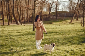 eine Frau steht im Wald mit ihrem Hund und telefoniert