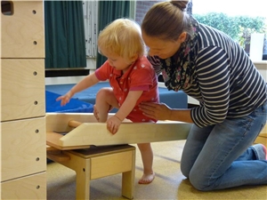 Physiotherapeutin übt mit Kind an einer Sprossenwand