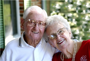 Ein älteres Paar, ihr Kopf liegt auf seiner Schulter, beide lachen