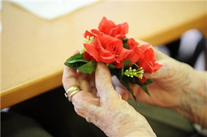 Hand einer älteren Frau hält Blumengesteck
