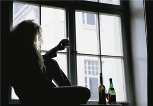 Ein Mann sitzt auf der Fensterbank und hält ein Glas Wein in der Hand