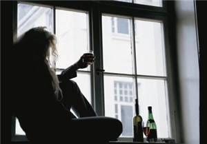 Süchtiger vor einem Fenster Ein Mann sitzt auf der Fensterbank und hält ein Glas Wein in der Hand
