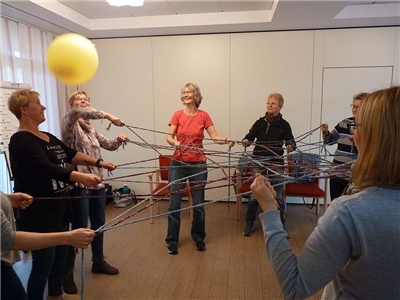 Frauen stehen im Kreis und spannen ein Netz zwischen sich. Auf dem Netz balancieren sie einen Ball.