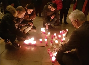 Menrere Menschen zünden Kerzen auf dem Boden der Stadtpfarrkirche an