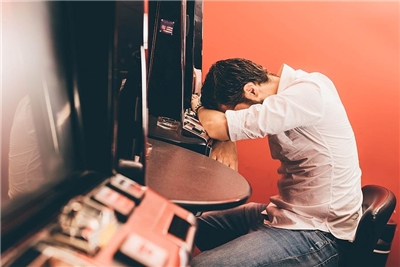 Ein Mann sitzt schlaftrunken vor einem Spielautomat.