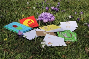 Gestaltete Ostergrußkarten liegen auf dem Rasen.