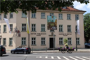 Bei strahlendem Sonnenscheinblicken wir auf die Geschäftsstelle des Caritasverbandes in der Wilhelmstr. 2 in Fulda. Über der Haustür ist ein Großplakat der diesjährigen Kampagne aufgehängt. Im oberen 