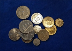 Auf einem dunkelblauem Samdtuch liegen viel unterschiedlich kleine und große Münzen in unterschiedlich schimmernden Farben. 