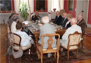 Wir sind zu Gast beim unserem Bischof. Im Gästezimmer haben sich 10 Personen mit ihm um einen großen Tisch versammelt. 