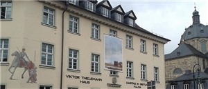 Wir blicken auf die Caritas Geschäftsstelle in der Wilhelmstraße. Ein großes Plakat von der Jahreskampagne ist in der Mitte des Gebäudes zu sehen. 