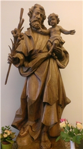 Wir sehen eine Holzfigur vom Heilgen Josef. Er trägt auf seinem Arm das Jesuskind.