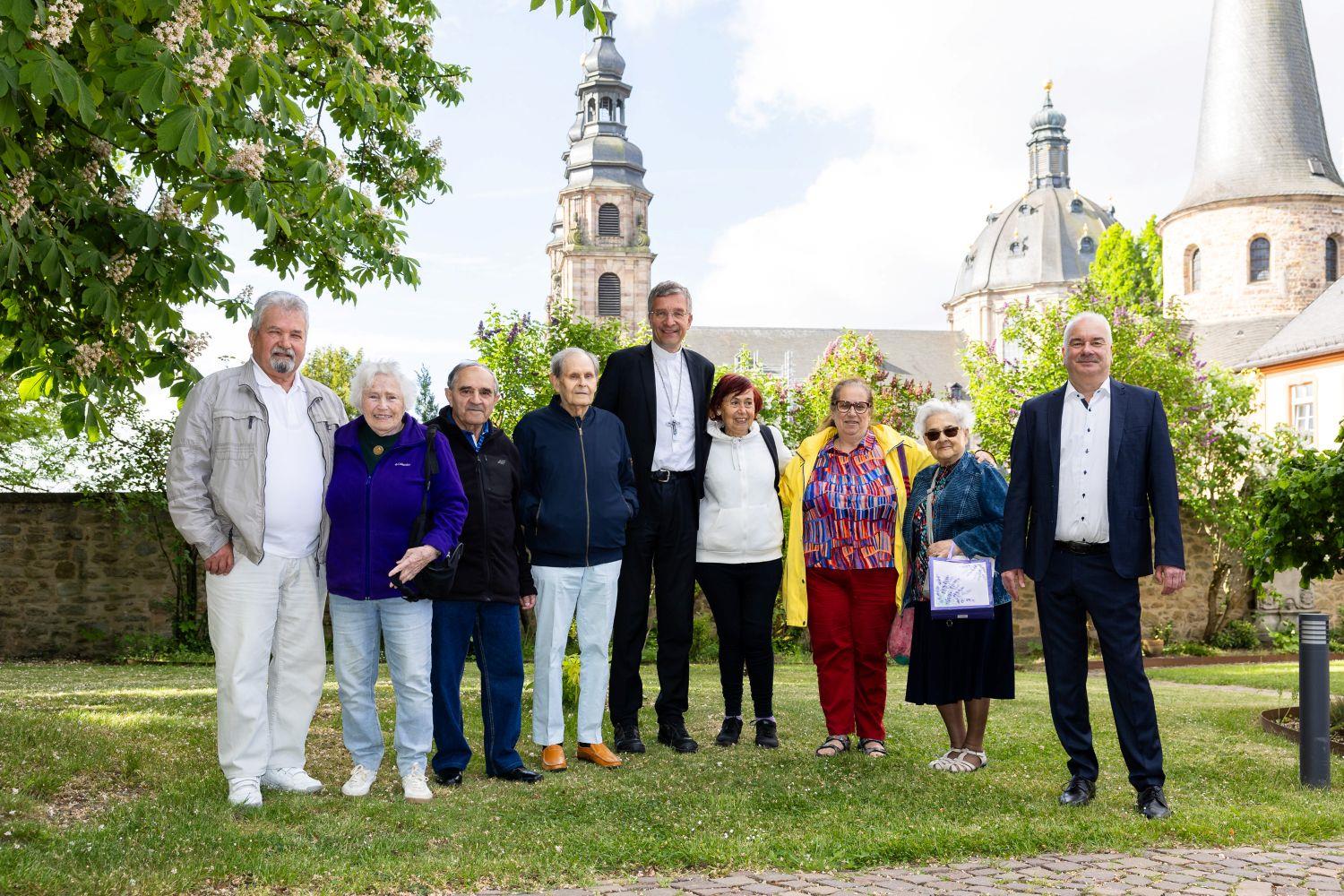 Eine Gruppe Personen steht im Sonnenschein im Grünen