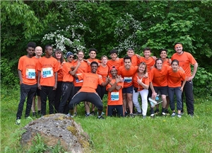 Die Teilnehmer des Challengelaufes tragen orange T-Shirts und haben sich zu einer Gruppe in mehreren Reihen aufgestellt. 