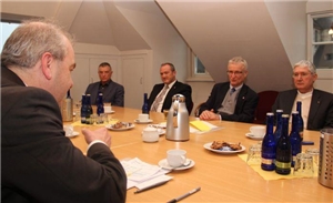 Die Verantwortlichen von Staat und Caritas sitzen am großen Tisch in der Geschäftsstelle des Verbandes.