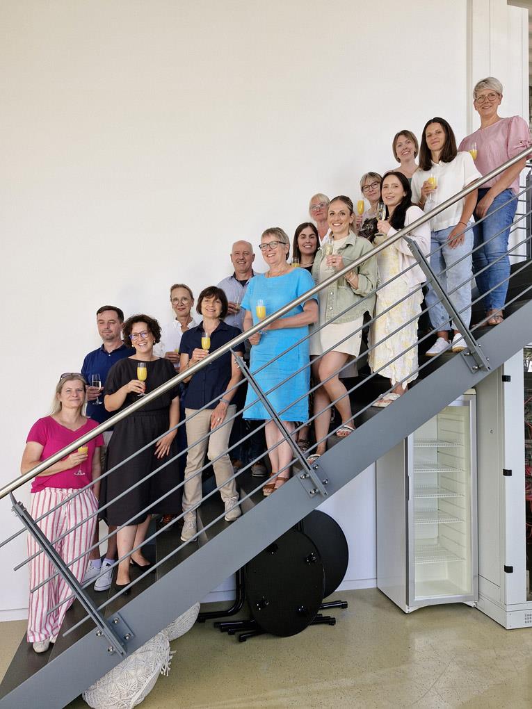 Auf einer Treppe stehen das Team der Caritas Pflegeschule und die neuen Sprachförderkräfte