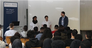 Zwei Schüler berichten vor den Teilnehmern über ihre Arbeit.