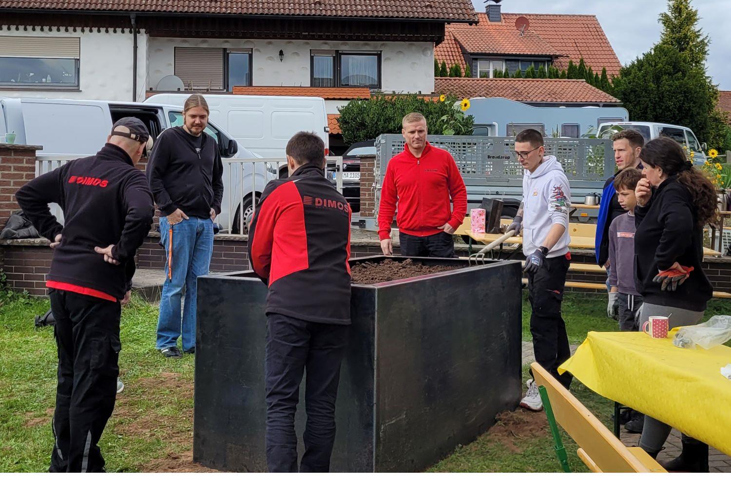 mehrere Personen neben einem aufgebauten Hochbeet