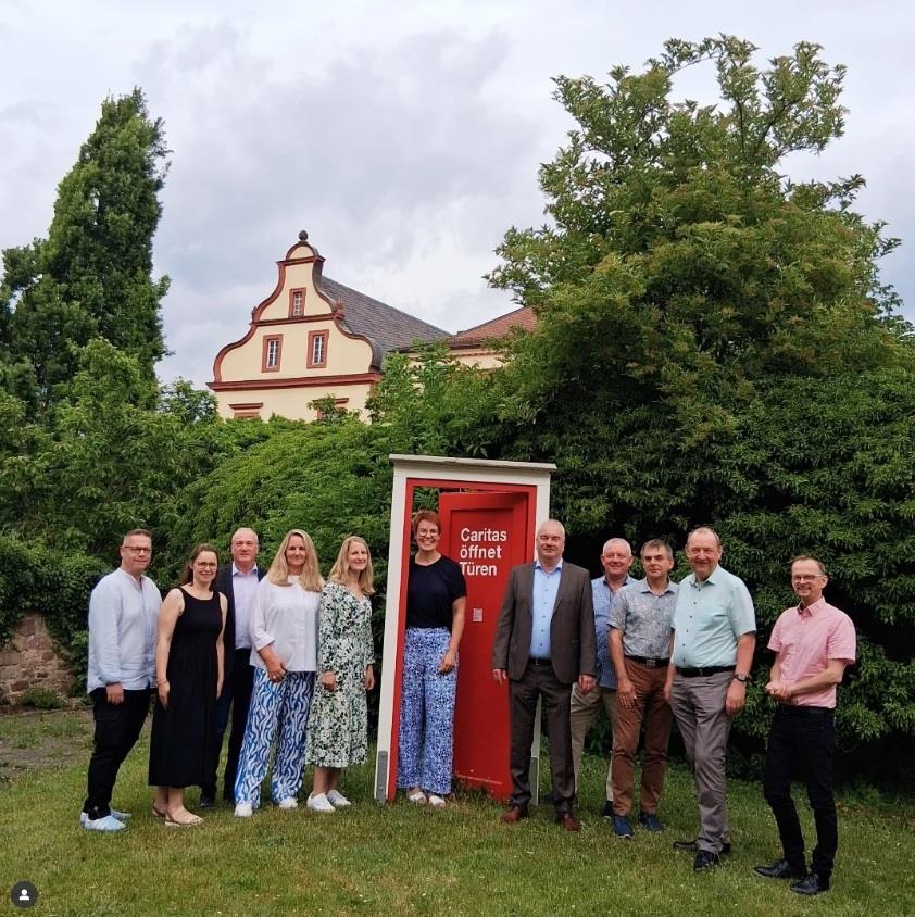 Mehrere Personen im Garten der Caritas an der roten Tür