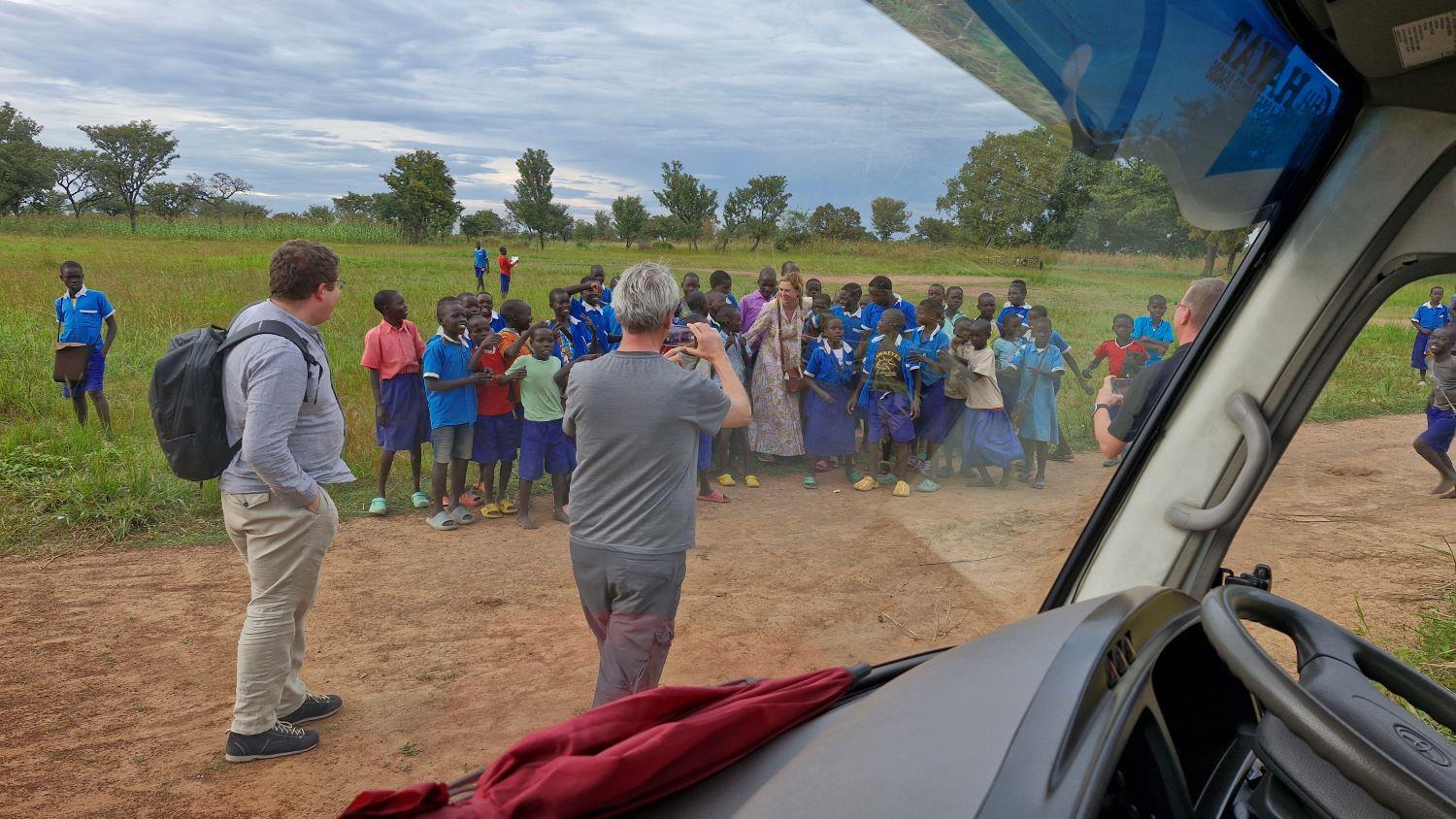 In Uganda am Strassenrand stehen Kinder in Schuluniform