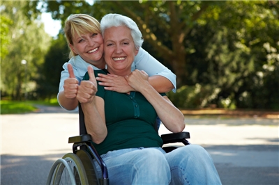 eine Rollstuhlfahrerin mit Betreuerin bei einem Spaziergang