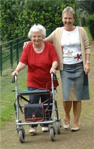eine jüngere Frau begleitet eine ältere Dame beim Spaziergang