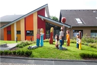 Stiftung Die Gute Hand Blick auf den Eingang des Multifunktionsraums Prälat Freudenberg mit den bunten Holzfiguren