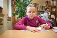 Ein Mädchen sitzt am Tisch und macht Hausaufgaben