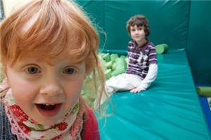 Heilpaedagogisches_Kinderdorf_Biesfeld Ein Mädchen und ein Junge auf dem Rand des Schaumstoffkissenbeckens im Psychomotorikraum