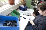 Verschiedene Zubehörteile und eine Montagebeschreibungen für Garagentore werden von einer Mitarbeiterin in Kunststoffbeutel verpackt